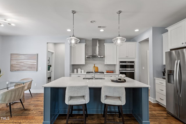kitchen with wall chimney range hood, dark wood-style flooring, stainless steel appliances, decorative backsplash, and visible vents