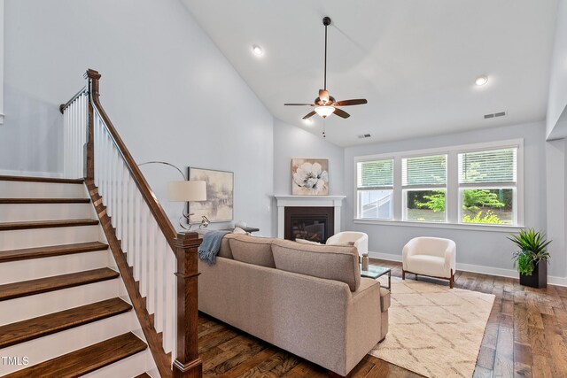 living room featuring visible vents, stairs, a glass covered fireplace, lofted ceiling, and a ceiling fan
