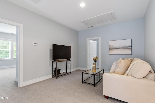living room with baseboards, attic access, and light carpet