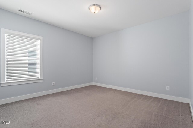 carpeted spare room featuring baseboards and visible vents