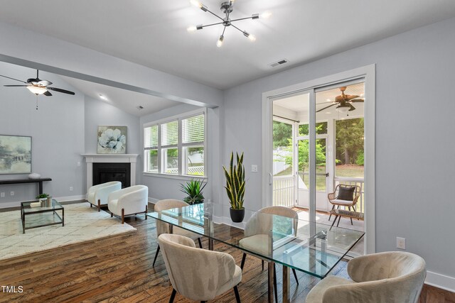 dining area featuring visible vents, baseboards, ceiling fan with notable chandelier, dark wood-style floors, and lofted ceiling