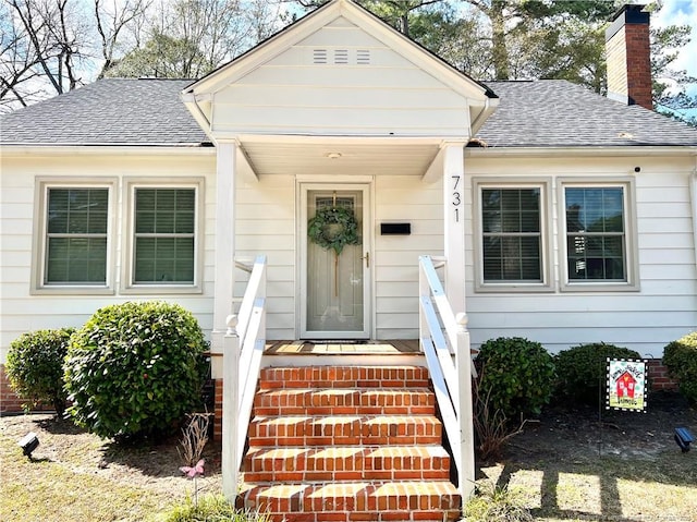 property entrance with a chimney and roof with shingles