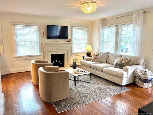 living room with a brick fireplace, crown molding, baseboards, and hardwood / wood-style flooring