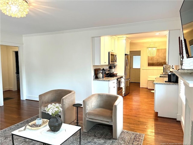 living area with wood finished floors and ornamental molding