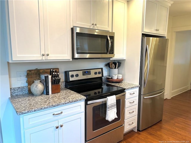 kitchen featuring light stone counters, appliances with stainless steel finishes, wood finished floors, and white cabinetry