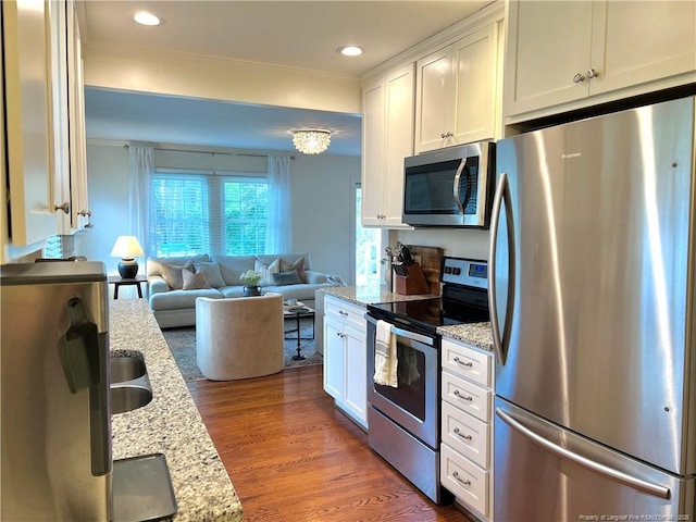 kitchen featuring open floor plan, dark wood-type flooring, appliances with stainless steel finishes, and white cabinets