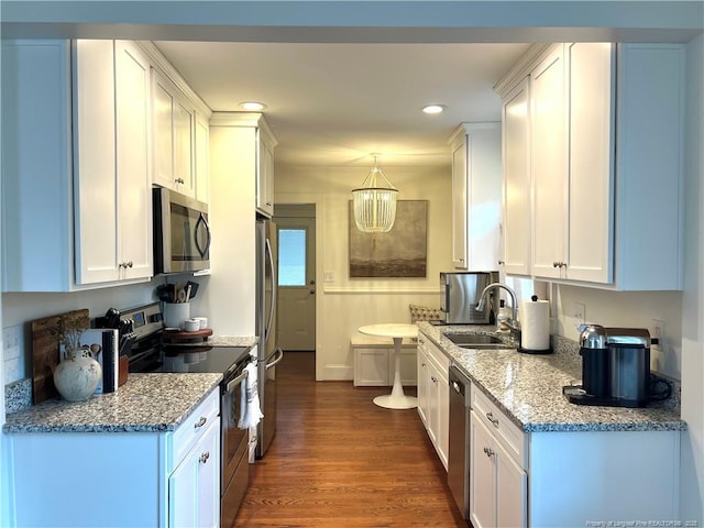 kitchen with light stone countertops, a sink, stainless steel appliances, dark wood-type flooring, and white cabinetry