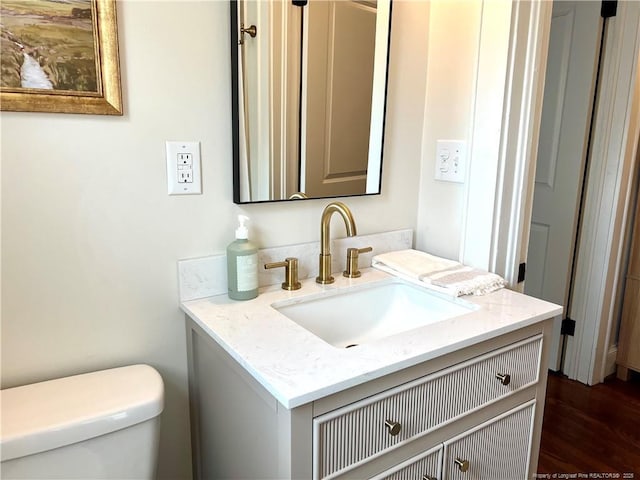 bathroom with vanity, toilet, and wood finished floors