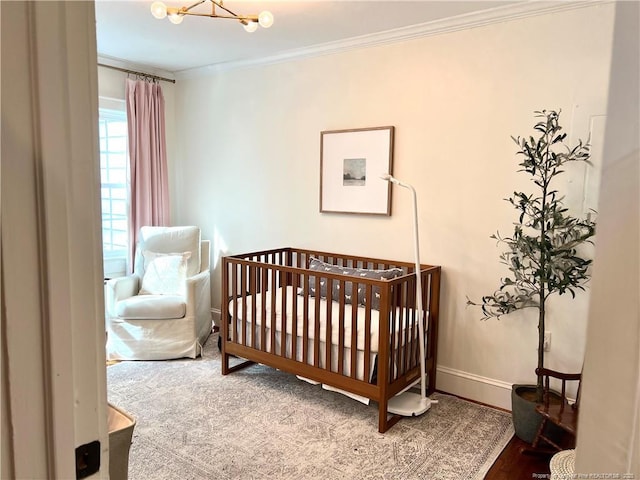 bedroom with a crib, baseboards, ornamental molding, and a chandelier