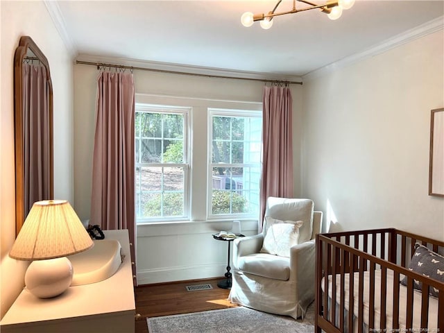 bedroom featuring wood finished floors, visible vents, baseboards, a crib, and crown molding