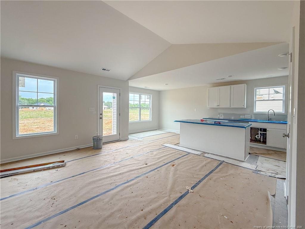 266 Guard Ln, Parkton, NC 28371 - kitchen featuring white cabinets, open floor plan, lofted ceiling, baseboards, and a sink