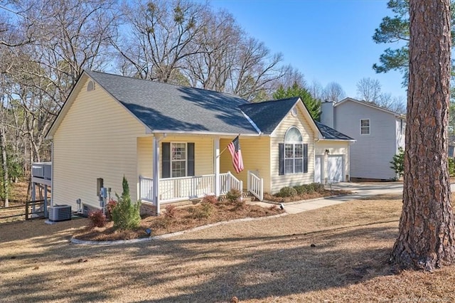 view of front of home with driveway, a garage, covered porch, and central AC