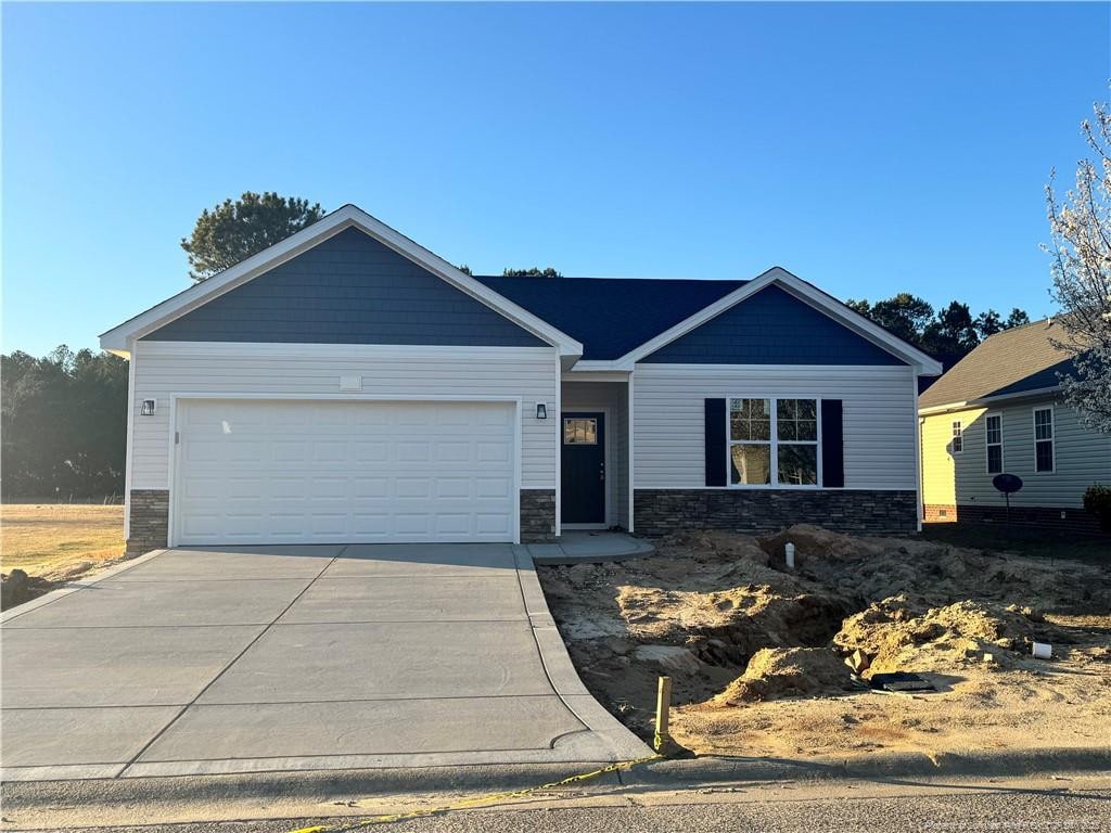 view of front facade with a garage, stone siding, and concrete driveway