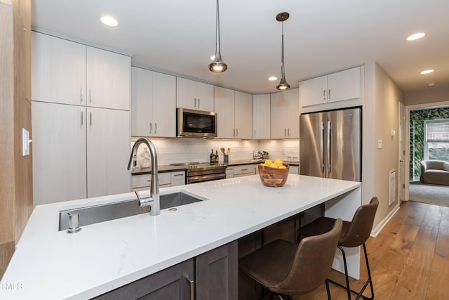 700 Bishops Park Dr Unit 205, Raleigh, NC 27605 - kitchen featuring appliances with stainless steel finishes, light wood-style flooring, decorative light fixtures, tasteful backsplash, and a kitchen breakfast bar
