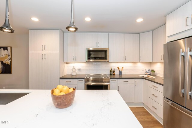 700 Bishops Park Dr Unit 205, Raleigh, NC 27605 - kitchen with stainless steel appliances, backsplash, light wood finished floors, decorative light fixtures, and recessed lighting
