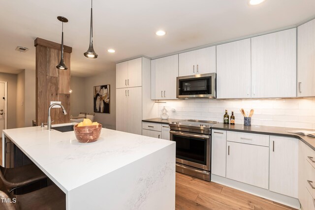 700 Bishops Park Dr Unit 205, Raleigh, NC 27605 - kitchen with stainless steel appliances, a sink, light wood-type flooring, recessed lighting, and tasteful backsplash