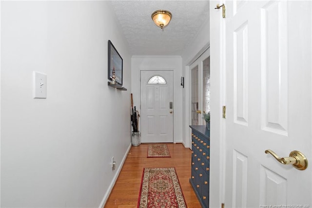 doorway to outside featuring baseboards, a textured ceiling, and light wood-style floors