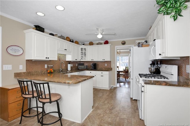 kitchen featuring white appliances, crown molding, a peninsula, and a sink