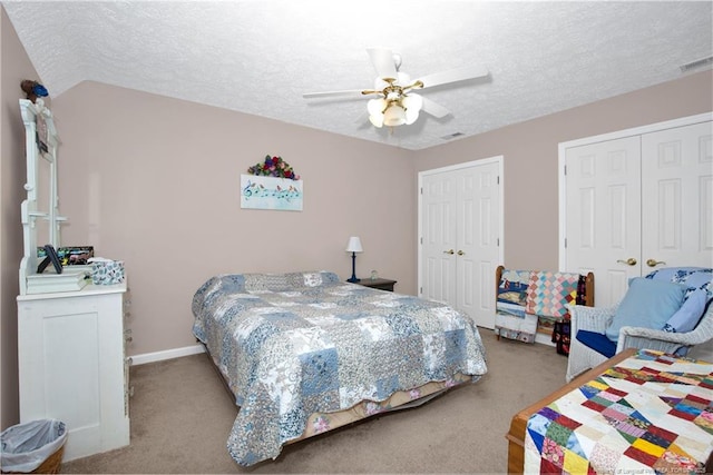 bedroom with a ceiling fan, visible vents, two closets, and a textured ceiling