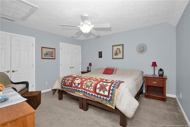 carpeted bedroom featuring visible vents, a textured ceiling, attic access, and baseboards