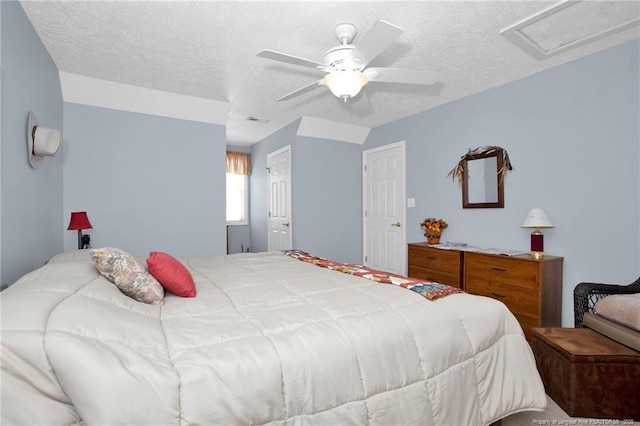 bedroom with attic access, visible vents, a textured ceiling, and a ceiling fan