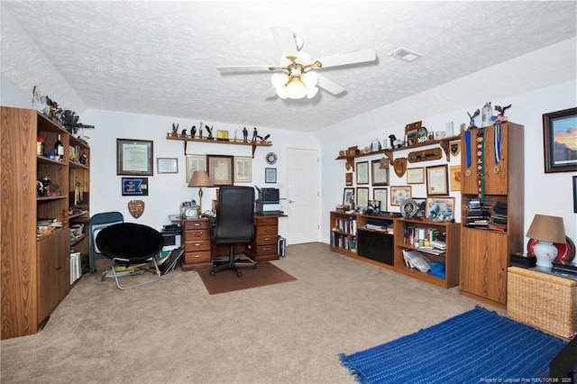 home office with visible vents, carpet flooring, a textured ceiling, and ceiling fan