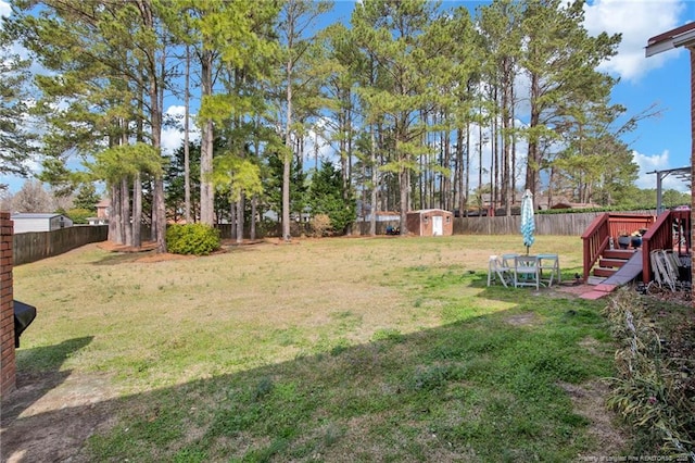 view of yard with an outbuilding, a fenced backyard, and a shed