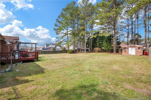 view of yard with a fenced backyard, a wooden deck, an outdoor structure, and a shed