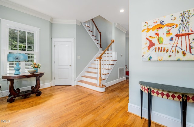 stairs with visible vents, baseboards, wood finished floors, and crown molding