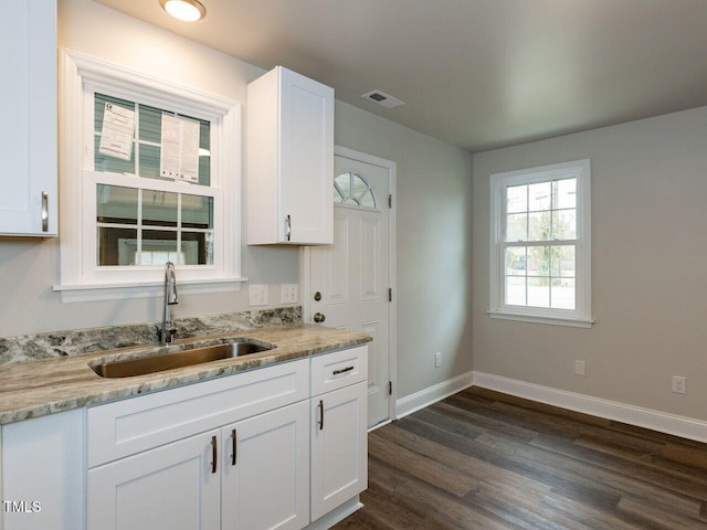kitchen with a sink, white cabinets, baseboards, dark wood finished floors, and light stone countertops