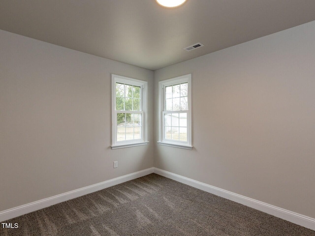 unfurnished room featuring baseboards and dark colored carpet