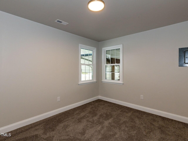 unfurnished room featuring dark colored carpet and baseboards
