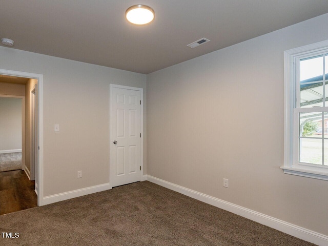 unfurnished bedroom featuring dark carpet and baseboards