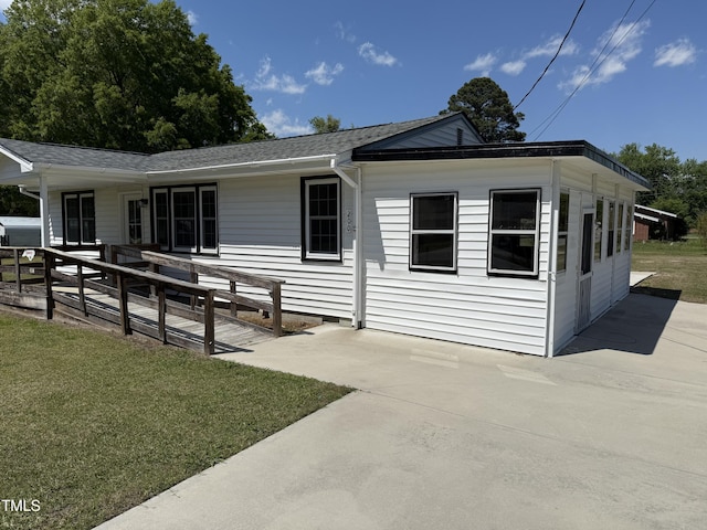 view of front of home featuring a front lawn, roof with shingles, and a patio