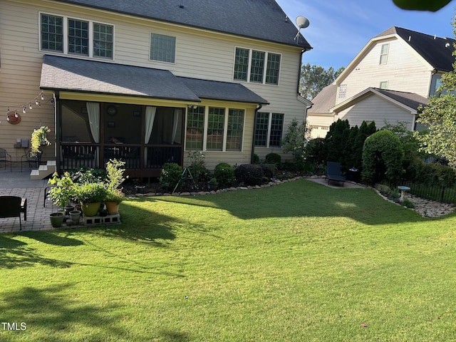 rear view of property with a yard, a sunroom, and a patio area