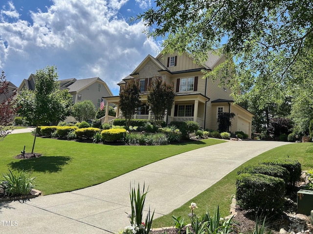craftsman house featuring board and batten siding, a front yard, driveway, and a garage