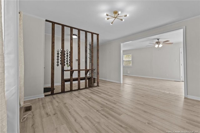 interior space with baseboards, ceiling fan with notable chandelier, wood finished floors, and ornamental molding