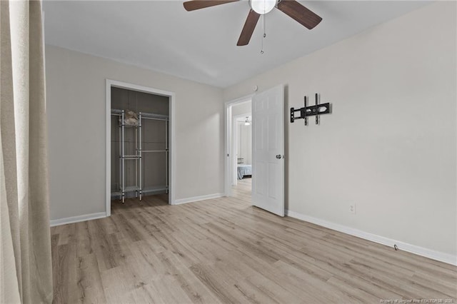 unfurnished bedroom with a closet, baseboards, light wood-style flooring, and a ceiling fan