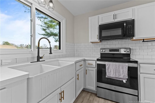 kitchen with backsplash, light countertops, electric stove, and black microwave