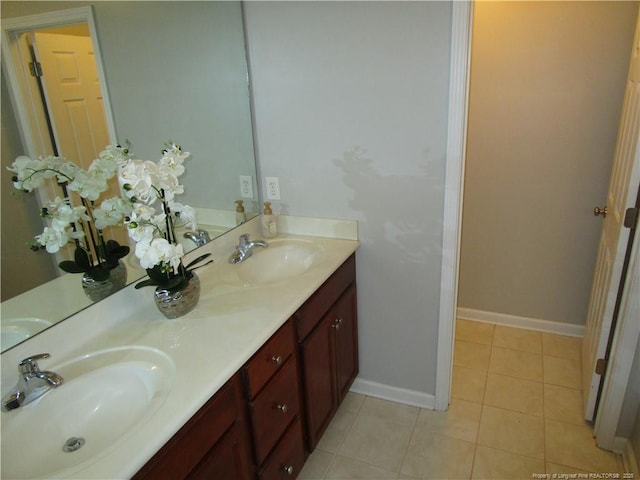 full bath with a sink, baseboards, double vanity, and tile patterned floors