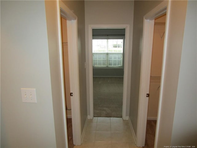 hall with light tile patterned flooring, light colored carpet, and baseboards