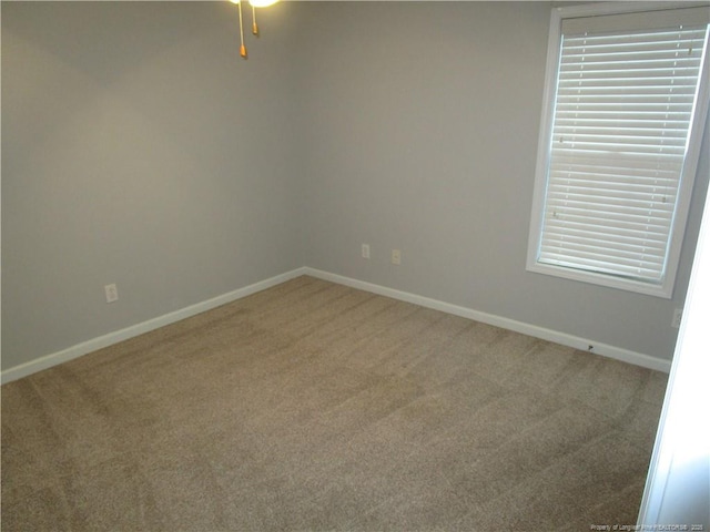 carpeted spare room with a ceiling fan and baseboards