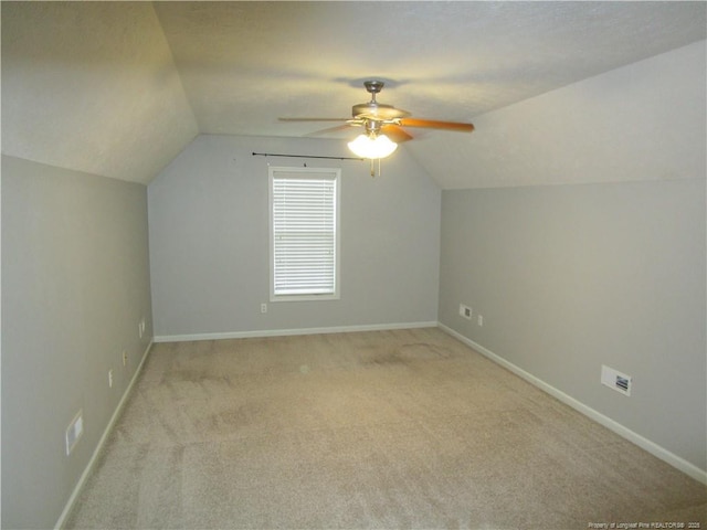 bonus room with a ceiling fan, a textured ceiling, baseboards, light colored carpet, and vaulted ceiling