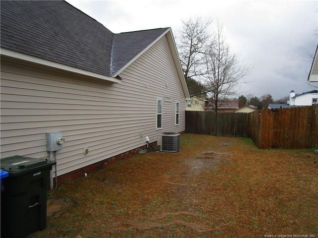 view of side of property with central air condition unit, a shingled roof, and fence