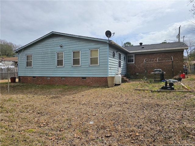 rear view of house with crawl space and fence