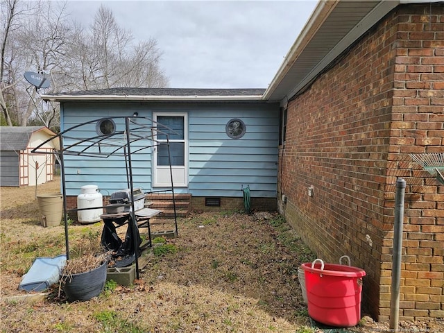 view of side of property with crawl space, a storage shed, an outdoor structure, and entry steps