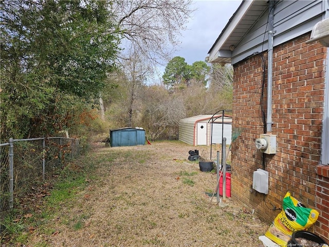 view of yard featuring a storage unit, an outdoor structure, and fence