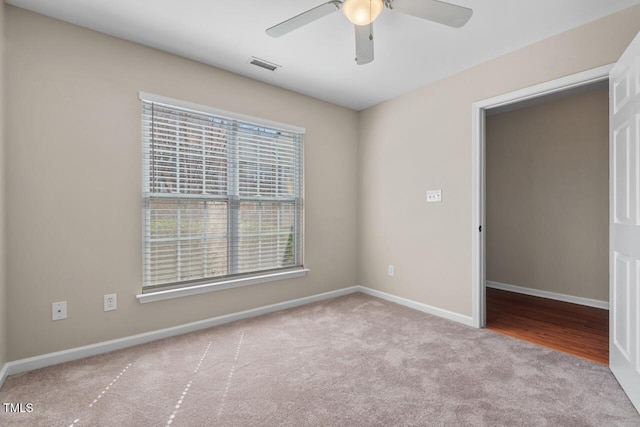 carpeted spare room with baseboards, ceiling fan, and visible vents