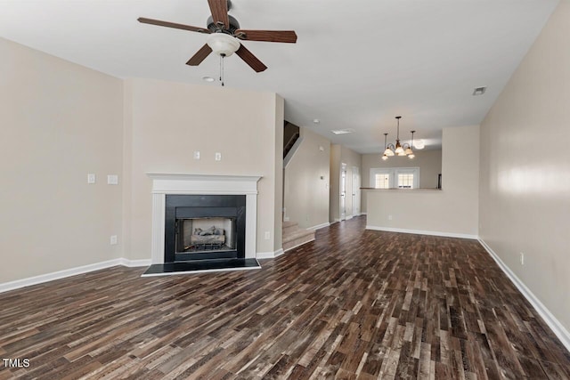 unfurnished living room with a fireplace with raised hearth, baseboards, wood finished floors, and ceiling fan with notable chandelier