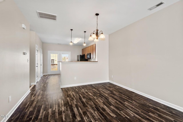 unfurnished living room featuring dark wood-style flooring, a notable chandelier, visible vents, and baseboards